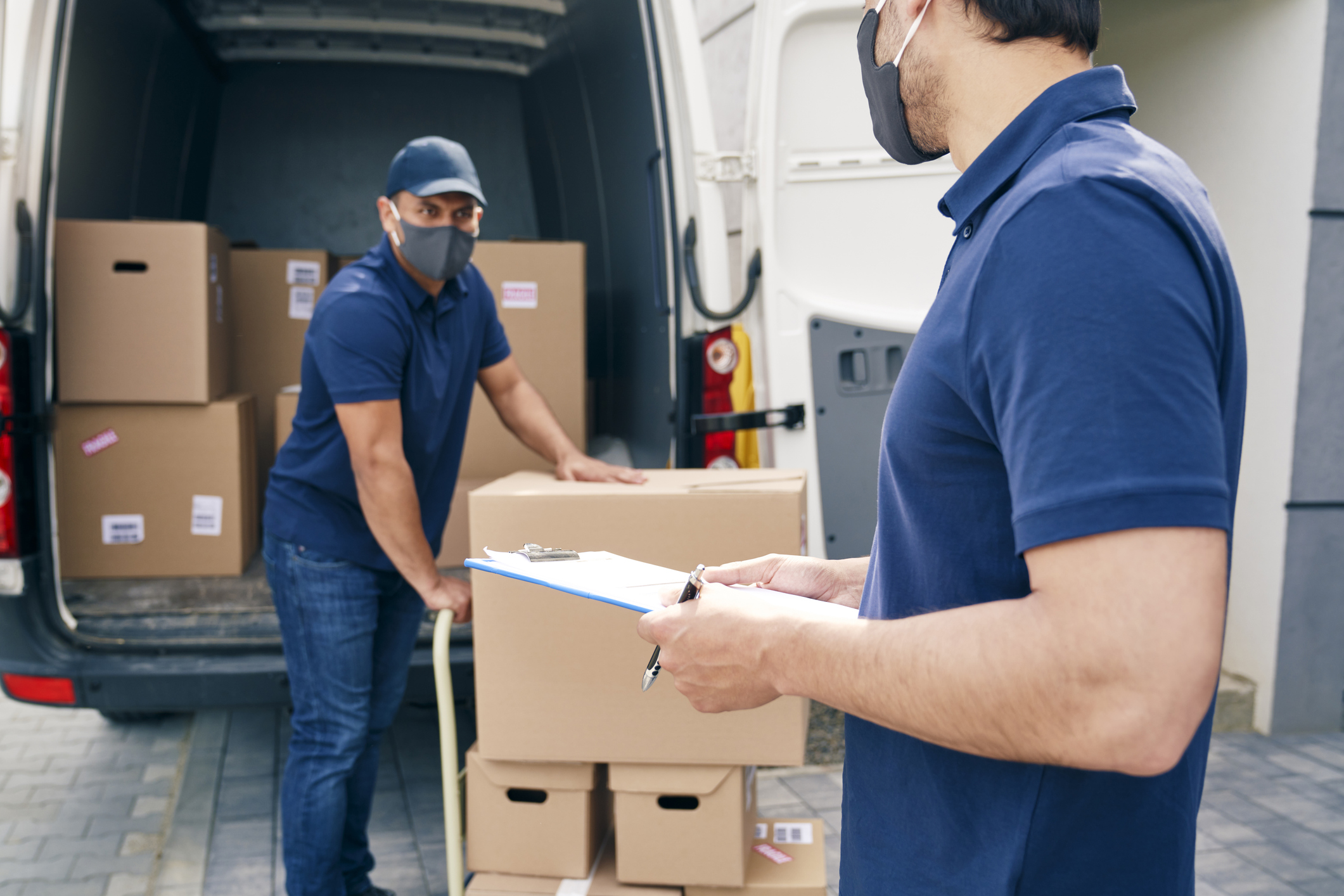 Zwei Personen besprechen den Transport von Kartons vor einem Lieferwagen